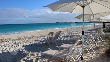 Vlak bij het strand, wit zand, ligstoelen aan het strand, parasols