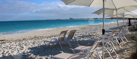 Vlak bij het strand, wit zand, ligstoelen aan het strand, parasols