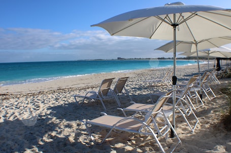Una playa cerca, arena blanca, sillas reclinables de playa, sombrillas