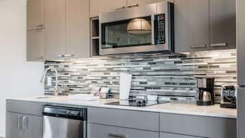 Uma cozinha moderna com eletrodomésticos de aço inoxidável, painel de azulejos e máquina de lavar louça.