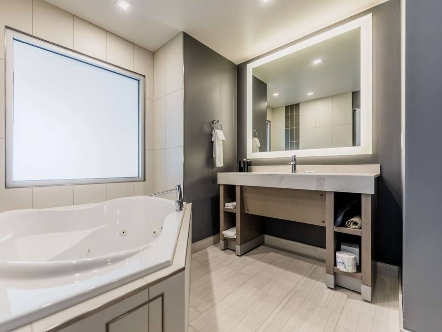 A modern bathroom with a freestanding bathtub, a large mirror, and a vanity with storage.