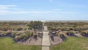 A wooden boardwalk leading to a beach area with dunes and sparse vegetation. - 6C Mariners Walk | AvantStay | Easy Pool + Beach Access (Isle of Palms)