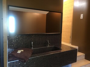 Bathroom features a clean design with a large mirror and a bathtub.