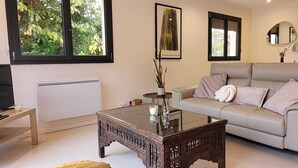 A modern living room with a beige sofa, a glass coffee table, a TV, and a radiator. - Villa in Dieulefit in Drome Provençale with views of nature and mountains (Dieulefit)