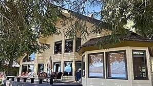 A two-story building with a porch, large windows, and a covered seating area. - McCall Lakefront Cabin with Dock & Stunning Views (McCall)