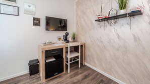 Une chambre moderne avec un bureau en bois, une télévision et une étagère ornée d’objets décoratifs.