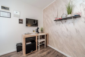 A modern room with a wooden desk, a television, and a shelf with decorative items. - Guesthouse Kod Spavalice (Vir)