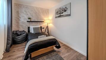 Une chambre à coucher avec un lit, une lampe de chevet et un tableau au mur.