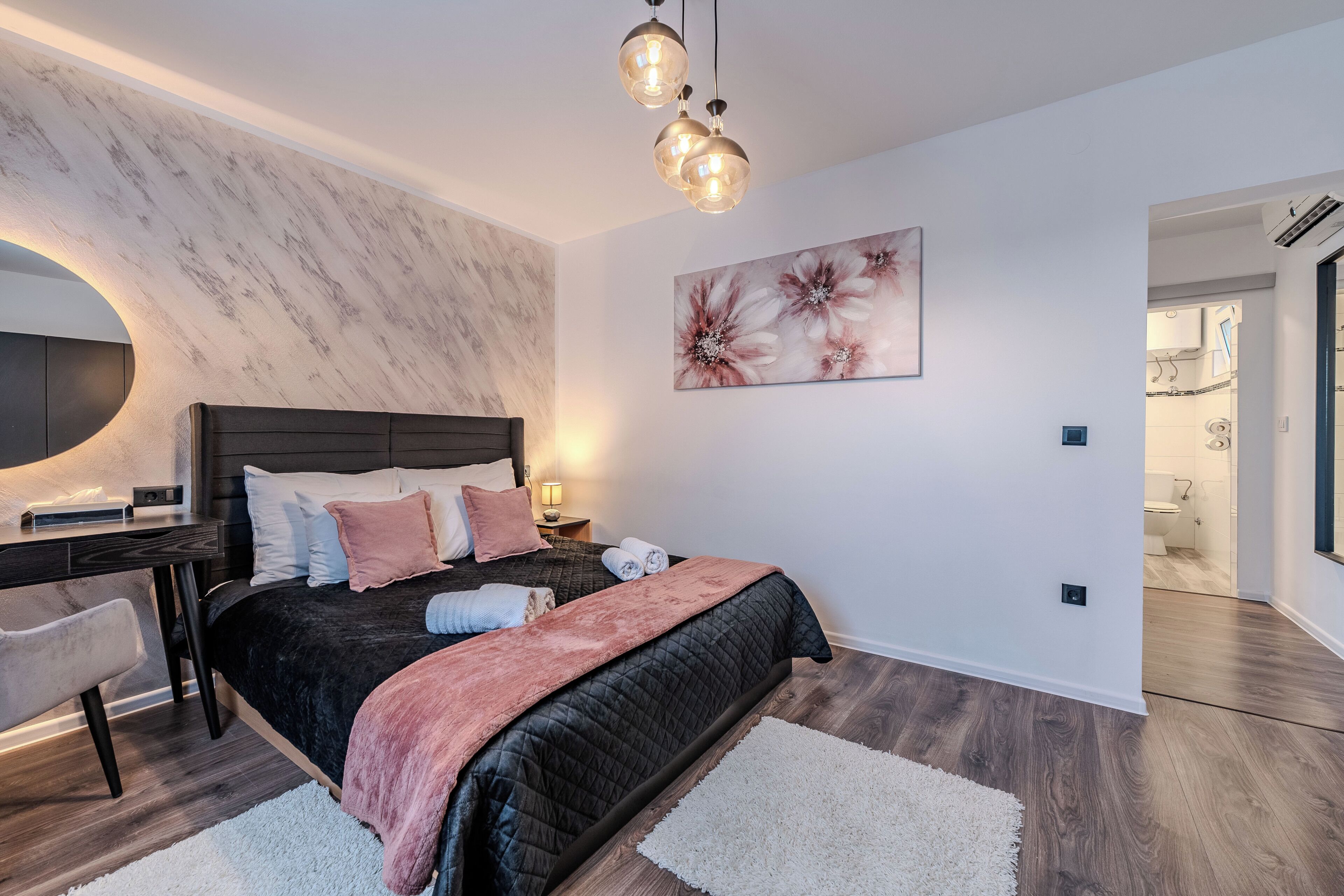 Ein modernes Schlafzimmer mit Bett, Nachttisch, Lampe und Kunstwerk.