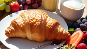 A breakfast setting with a croissant, fruit, juice, and milk on a table. - Guesthouse Kod Spavalice (Vir)