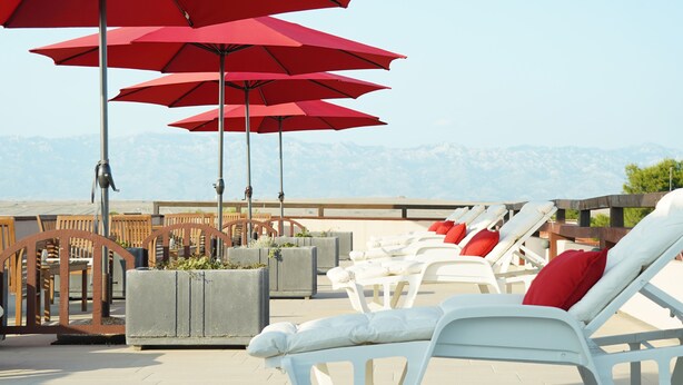 Outdoor lounge chairs and red umbrellas on a terrace with a mountain view. - Guesthouse Kod Spavalice (Vir)