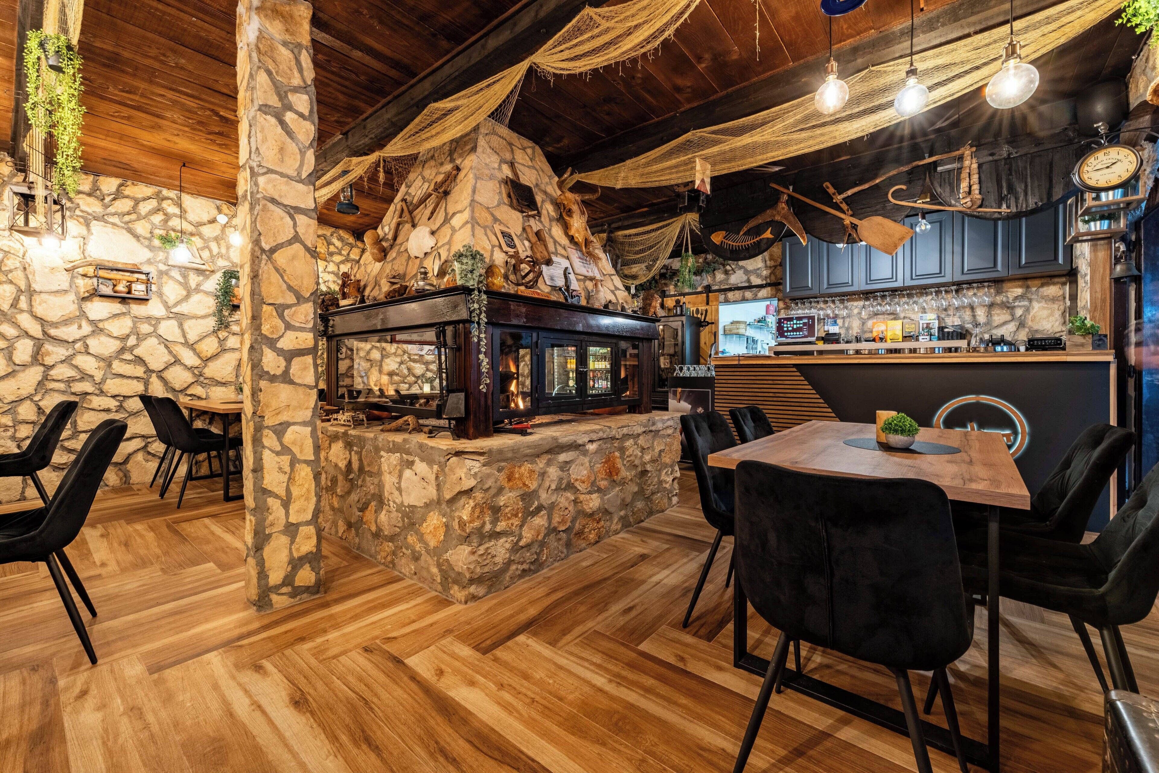 Un intérieur rustique avec une cheminée en pierre, un plancher en bois et un coin bar.