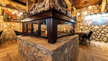 A stone fireplace with a glass enclosure, wooden beams, and a rustic interior.