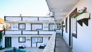 A two-story building with a stone pool, outdoor seating, and hanging flower baskets. - Guesthouse Kod Spavalice (Vir)