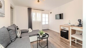 Un salon moderne comprenant un canapé, une table basse, un téléviseur et un coin cuisine.