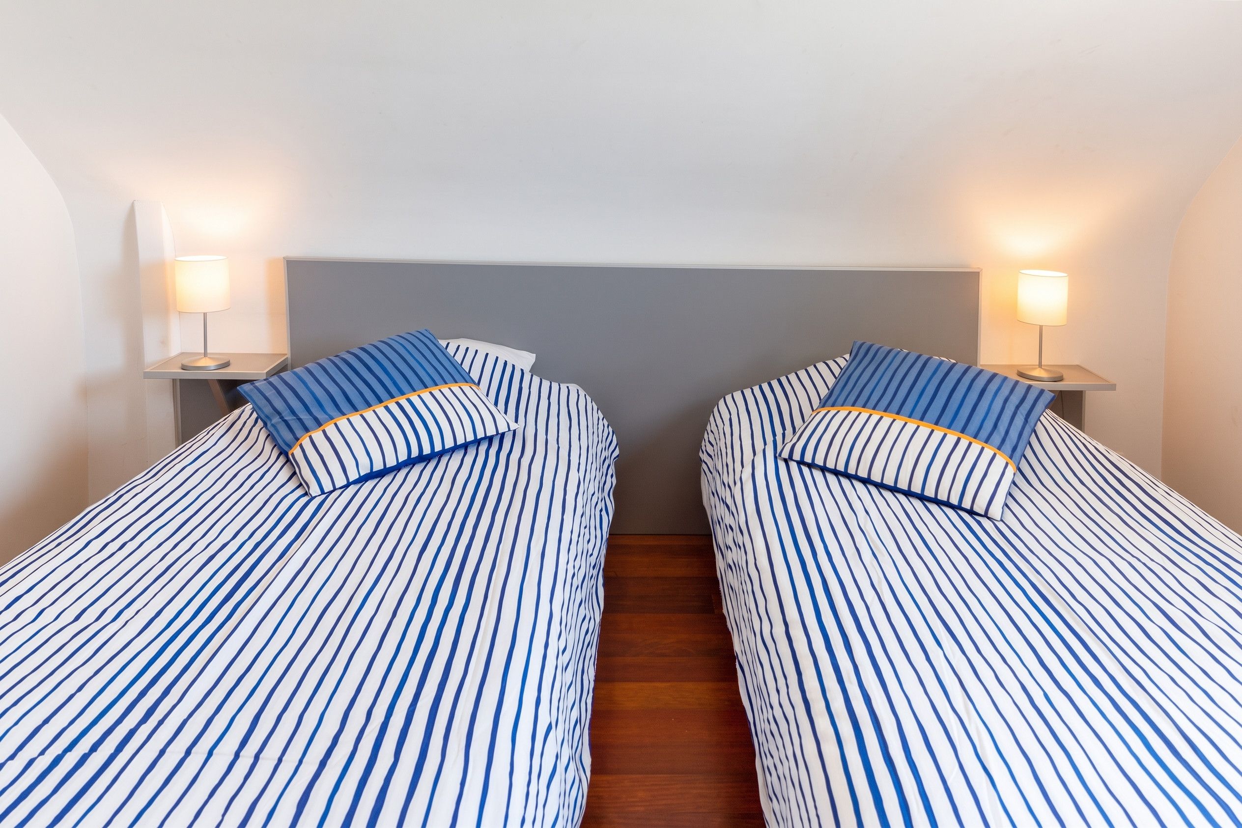 Une chambre avec deux lits simples, chacun doté d’une tête de lit et de lampes de chevet.