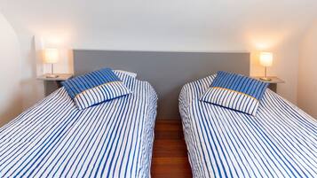 Une chambre avec deux lits simples, chacun doté d’une tête de lit et de lampes de chevet.