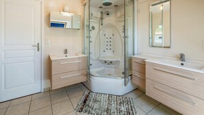 A modern bathroom with a glass-enclosed shower, a white sink, and a mirror above the vanity. - Homerez - House in Plurien (Plurien)