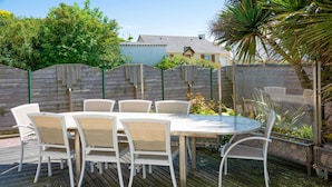 A round outdoor table with white chairs, surrounded by a wooden deck. - Homerez - House in Plurien (Plurien)