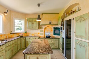 A kitchen with green cabinets, a granite countertop, and a built-in oven.
