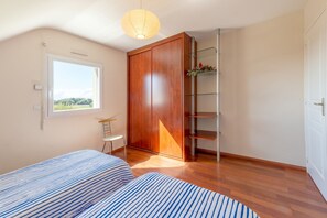 Quarto com cama, uma cadeira, guarda-roupa, janela e estante com plantas.