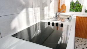 Uma cozinha moderna com fogão embutido, pia e janela com cortinas de renda.
