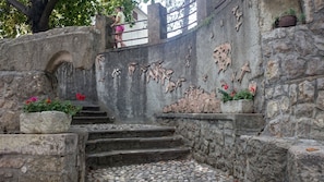 A stone staircase leading up to a wall with carved figures and floral decorations.
