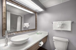Un baño con lavamanos blanco, un espejo, toallero y un inodoro.