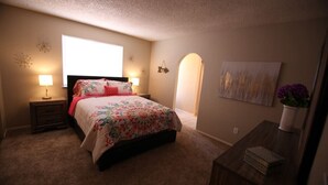 Une chambre à coucher avec un lit, des lampes de chevet, une table de chevet, une commode et une fenêtre.