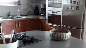 A modern kitchen with a central island, stainless steel appliances, and wooden bar stools. - 10-minute walk to the sea for 2 to 6 people (Le Relecq-Kerhuon)