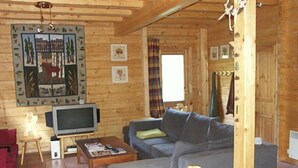 Ein gemütliches Blockhaus-Interieur mit Holzboden, einem großen Gemälde an der Wand, einem Fernseher, einer Couch und einem Couchtisch.