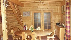 Ein Holzblock-Innenraum mit Esstisch und Stühlen, einer Küchenzeile und einer Treppe.