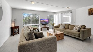 A modern living room with two sofas, a coffee table, and a TV. - Spacious apartment in very well maintained complex.  Walk to beach. (Point Lookout)