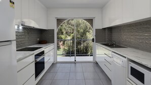 A modern kitchen with white cabinets, a double sink, and a built-in oven. - Spacious apartment in very well maintained complex.  Walk to beach. (Point Lookout)