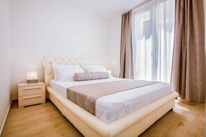 A bedroom with a bed, bedside table, and curtains.
