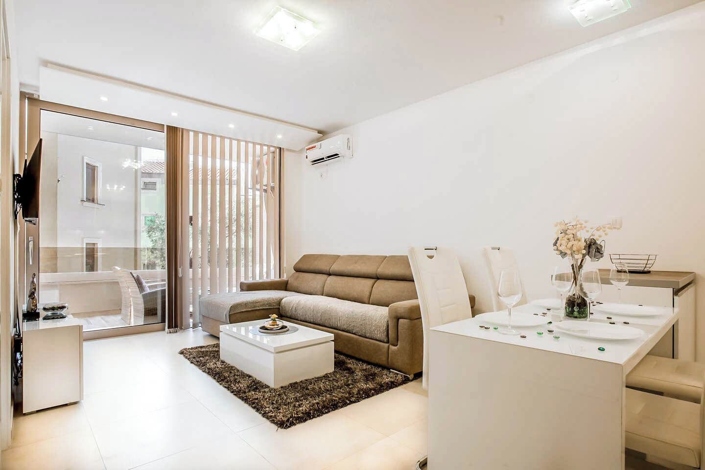 A modern living room with a sofa, coffee table, and dining area.