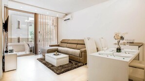 A modern living room with a sofa, coffee table, and dining area.