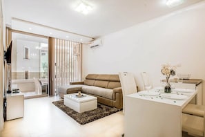 A modern living room with a sofa, coffee table, and dining area. - Lux Apartment Teodora Rafailovici 4-stars with swimming pool (Rafailovici)