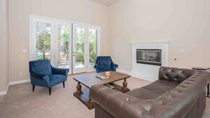 A living room with a brown leather sofa, two blue armchairs, a wooden coffee table, and a fireplace. - Hacienda near the Las Vegas Strip (Las Vegas Nevada)