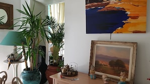 Une pièce avec un meuble en bois, un tableau encadré et une plante en pot.
