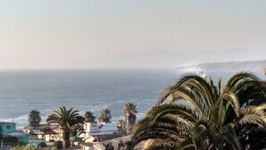 A coastal view with a lighthouse, palm trees, and buildings along the shore. - TerrazaMar EcoCabañas (Quintero)