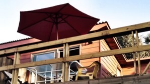 A wooden structure with a red umbrella, a window, and a chair. - TerrazaMar EcoCabañas (Quintero)