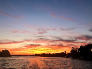 A sunset over a calm body of water with silhouettes of trees and boats. - Luxury 5 Star Rated Homosassa Home.  Prime location, ultra-clean, well designed  (Homosassa)