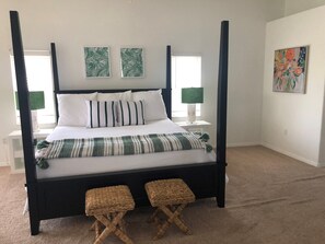 A four-poster bed with white bedding and striped pillows, two woven stools, and two wall-mounted lamps. - Luxury 5 Star Rated Homosassa Home.  Prime location, ultra-clean, well designed  (Homosassa)