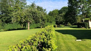 Ein gepflegter Garten mit verschiedenen Bäumen und ordentlich geschnittenen Hecken.
