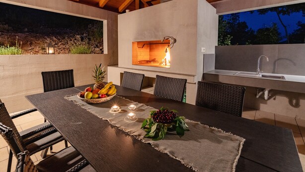 An outdoor dining area with a table set for two, a built-in grill, and a sink. - Beautiful villa with heated pool in Poljica Imotski - 8 people (Poljica)