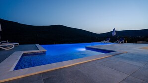 A swimming pool with a tiled edge and a view of a mountain in the background. - Beautiful villa with heated pool in Poljica Imotski - 8 people (Poljica)