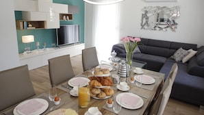 A modern dining area with a wooden table set for breakfast, a sofa, and a TV in the background. - Beautiful villa with heated pool in Poljica Imotski - 8 people (Poljica)