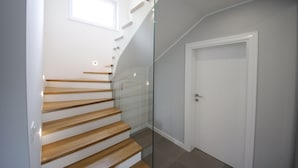 A modern staircase with wooden steps and glass railings, leading to a white door. - Beautiful villa with heated pool in Poljica Imotski - 8 people (Poljica)