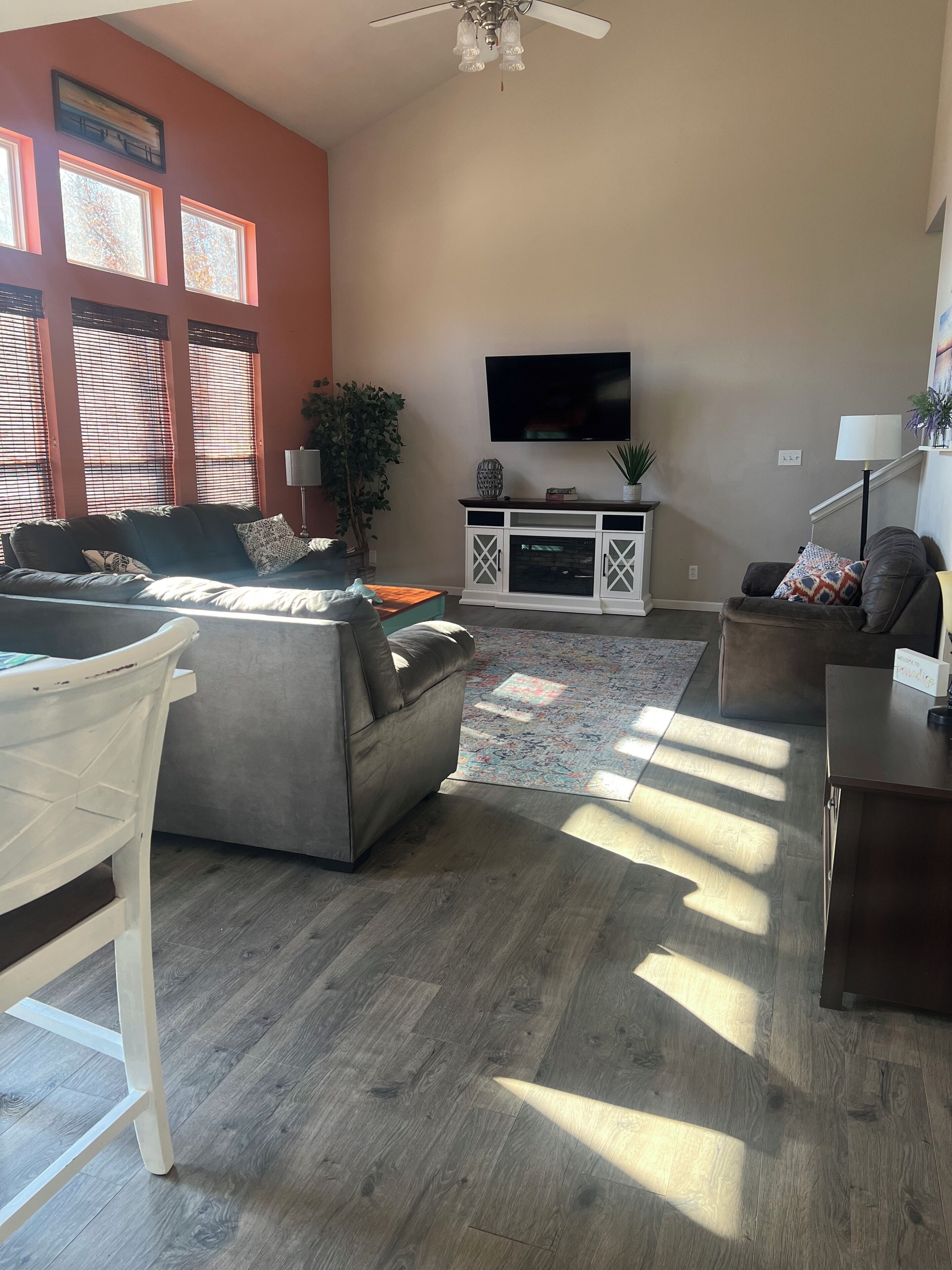 Un salon avec un canapé, une table basse, un téléviseur et un ventilateur de plafond.